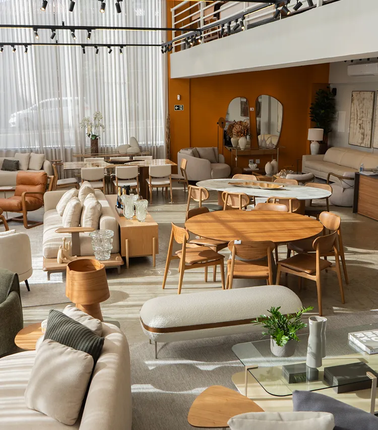 Showroom de móveis modernos com sofás, mesas e poltronas em tons neutros e madeira clara.