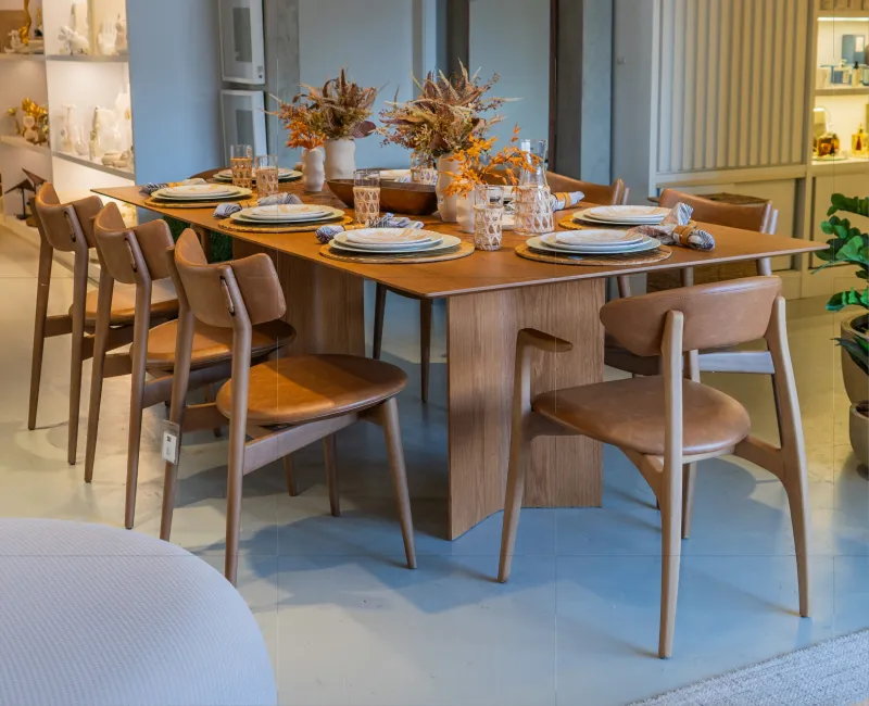 Sofá bege com várias almofadas azuis e mesa de centro decorada com plantas e vasos.