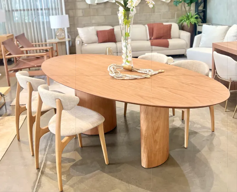 Mesa de jantar em pedra com veios marrom e cadeiras estofadas em couro caramelo.